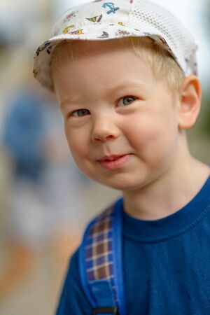 Portrait of a smiling boy in a blue T-shirt and a light cap.の写真素材