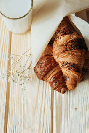 three croissants with chocolate and milk on wood tableの写真素材