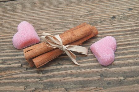 cinnamon and fruit candy in the form of heart on a wooden backgroundの写真素材