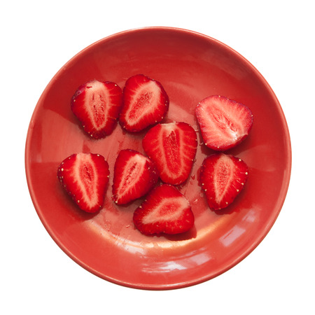 sliced strawberries on a red saucer on a white backgroundの写真素材