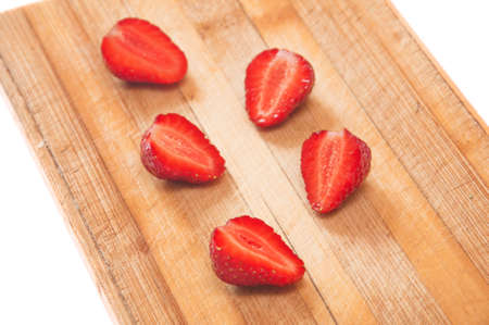 sliced strawberries on a wooden board on a white backgroundの写真素材