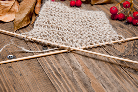knitting beige and red berries on a brown wooden backgroundの写真素材
