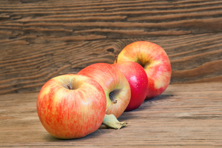 Four fresh red apples on a brown wooden backgroundの写真素材
