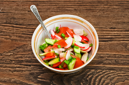vegetable salad in a white bowl on a brown wooden backgroundの写真素材