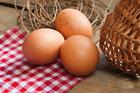 three eggs on the table on a checkered napkin with a basket and threads