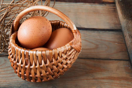 Eggs in a basket on a brown wooden backgroundの写真素材