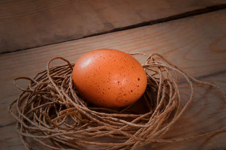 egg in a nest of thread on a brown wooden backgroundの写真素材