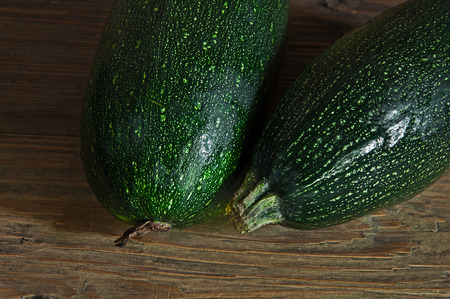 Two green zucchini on the wooden table brownの写真素材