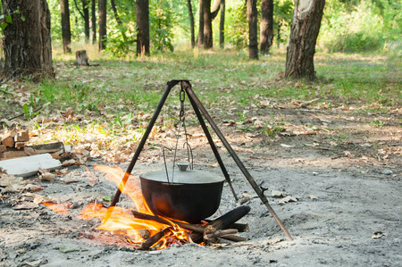 Cooking outdoors in summer forest on a fire in a kettleの写真素材