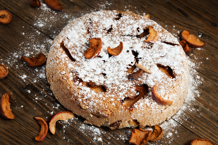 the sweet apple cake with powdered sugar on a wooden tableの写真素材