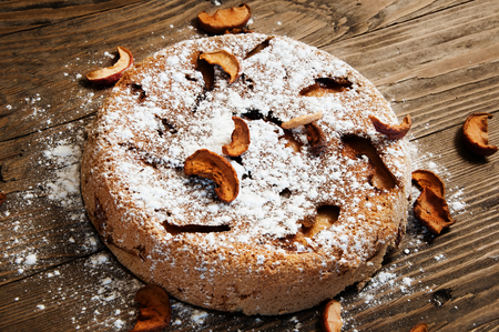 the sweet apple cake with powdered sugar on a wooden tableの写真素材