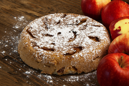 the sweet apple pie and fresh apples on a wooden tableの写真素材