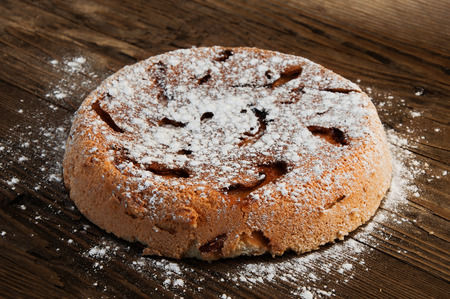 the sweet apple cake with powdered sugar on a wooden tableの写真素材
