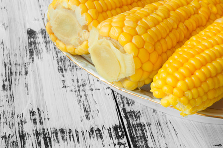 Tasty yellow corn on a plate on a white wooden backgroundの写真素材