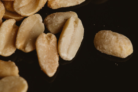 bunch of kernel peanuts on a dark background.