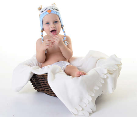 Beautiful baby in a cap owl sitting in a basketの写真素材