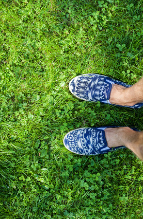 Feet in blue sneakers on green grass, top view, informal styleの写真素材