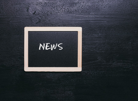 old small blackboard with wooden frame on textured black backgroundの写真素材