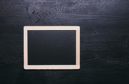 old small blackboard with wooden frame on textured black backgroundの写真素材
