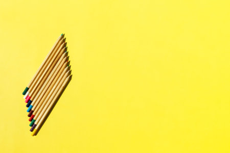 Bright mix colored wooden pencils in shape. Minimalistic geometric lines on yellow background. Top view, school or education concept.の写真素材