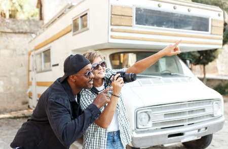 excited African American couple celebrating success, travel, overjoyed wife and husband received good news, online lottery win, approved mortgage loan, showing yes gesture. Nature flowering background.の写真素材