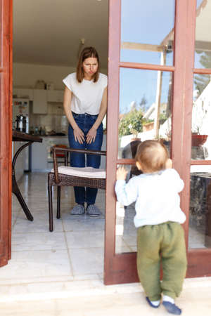 Focused baby boy holding moms hand and trying to walk at home. Full length. Parenthood and childhood concept.の写真素材