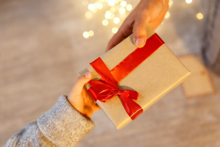 gift in the hands of a child and adult, congratulations on christmas day at home.