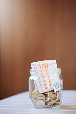 Turkish lira banknotes and coins in glass jar, woman hand. The paper currency of Turkey. Current Turkish liras are issued by The Central Bank of the Republic of Turkey. Financial crisis, saving conceptの写真素材