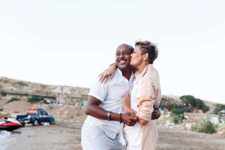 Mixed race smiling couple enjoying on vacation, tourist having fun walking on beachside, diversity and love conceptの写真素材