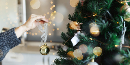 Closeup image of woman hand in sweater decorating Christmas tree with ball,christmas tree and...
