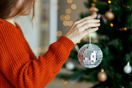 Closeup image of woman hand in sweater decorating Christmas tree with ball,christmas tree and bokehon backgroundの写真素材