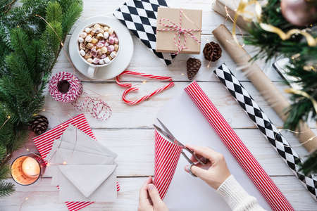 Getting ready for Christmas or New Year holiday. Flat-lay of decorations, ribbons, gift paper, door wreath, glittering balls, candy canes and cocoa with marshmallow ,top view. Christmas festive moodの写真素材