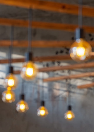 Blurred edison lamps hanging from the ceiling. Vintage style light bulbs decorating room. Loft...