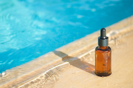 Amber bottle with serum in water on blue swimming pool background close-upの写真素材