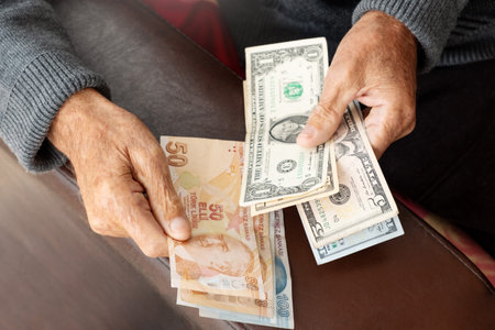 Senior wrinkled hands holding American US currency and Turkish Lira business or economy crisis concept with dollars bill banknotesの写真素材