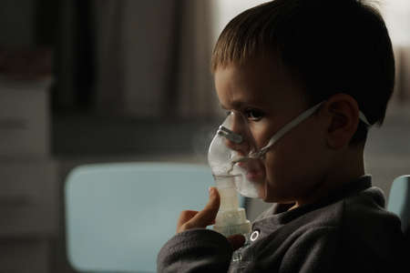 Little boy using nebulizer during inhaling therapy at homeの写真素材
