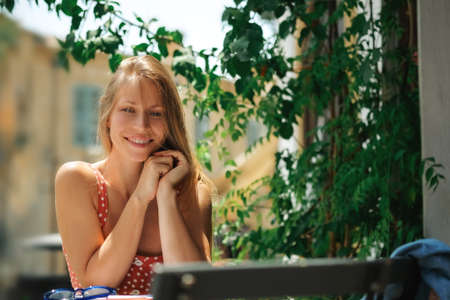 Happy young caucasian,millennial or gen z woman with long brunette looking on camera in modern outdoor cafe.Hipster Influencer using social networksの写真素材