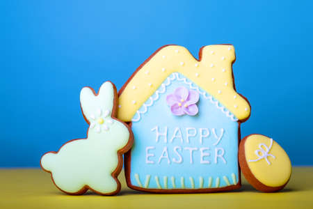 Text happy easter and a cookies decorated as an ornamented easter egg on blue backgroundの写真素材