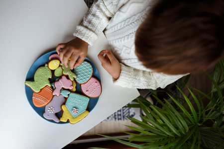 A child in his hands holding a plate with Easter eggs, bunny, chicken and house made from homemade...