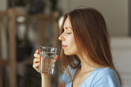 Portrait of young woman drinking pure glass of water, close up