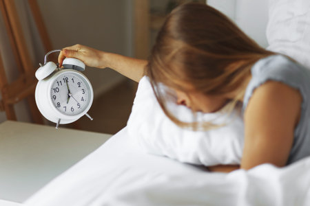 Woman sleep on the bed turns off the alarm clock wake up at the morning, Selective focus.