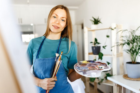 Woman artist holding paintbrush.Creative woman enjoying painting.Young beautiful woman in art...