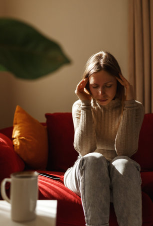 Lady lying touching temples.Young woman suffering headache, migraine, depression, sitting on sofa,...