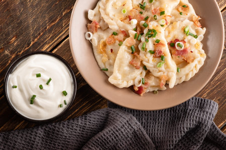Potato dumplings with sour cream on the wooden table. Traditional ukrainian food. Varenyky, vareniki, pierogi, pyrohy - dumplings with fillingの写真素材