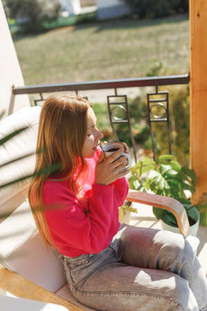 Young woman enjoying the view from apartment,drinking morning coffee on the balconyの写真素材
