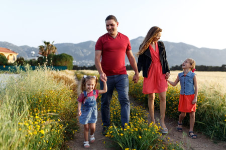 Happy family father of mother and two daughters sisters walking on countryside nature at...