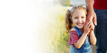 Little girl holding fathers hand,looking camera,smiling.Happy family, bonding, love. Summertime. Dad...