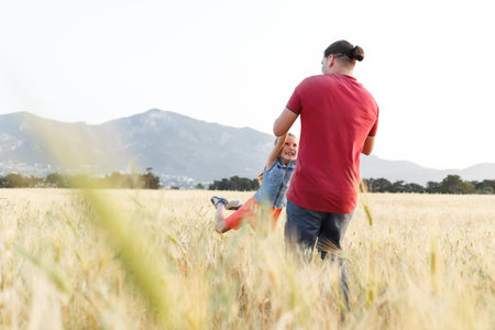Dad spins his daughter on field , having fun at sunset. Father plays with child. Happy family and childhood conceptの写真素材