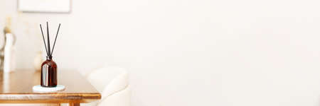 Aroma reed diffuser home fragrance with rattan sticks on a light background on wooden table in living room, bannerの写真素材