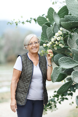 Close up portrait of happy older woman standing outside in summerの写真素材